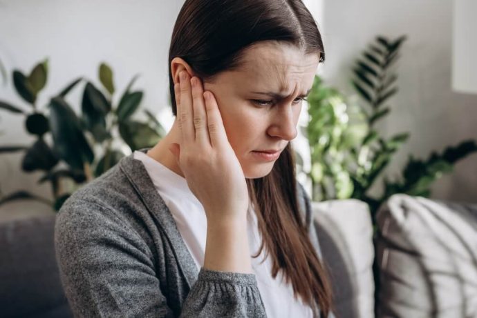 woman holding her ear because she has ear problems