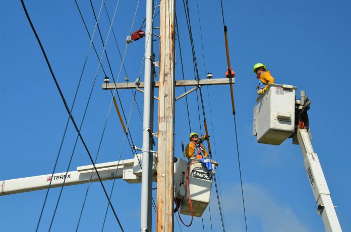 two linemen on cherry pickers checking on power lines