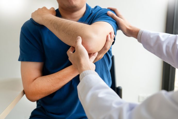 doctor inspecting man's injured shoulder
